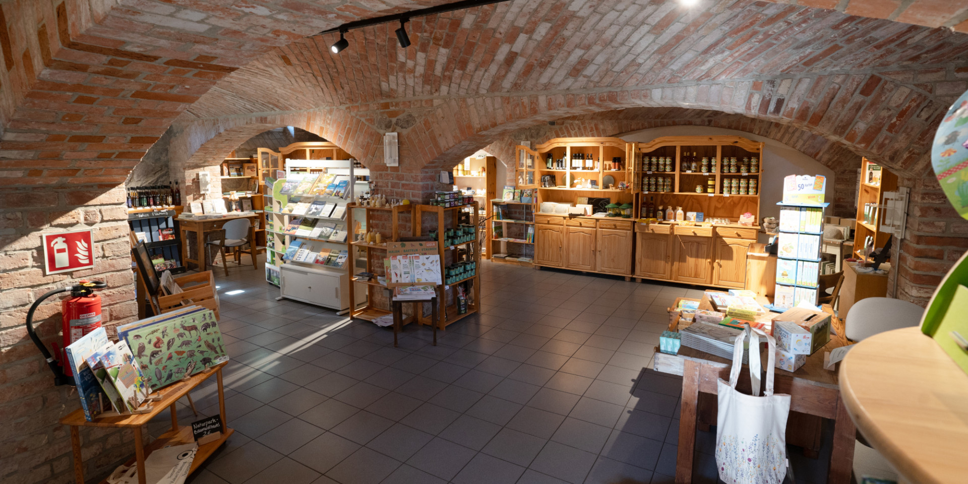 Holzregale mit verschiedenen Produkten im Gewölbekeller aus Backstein